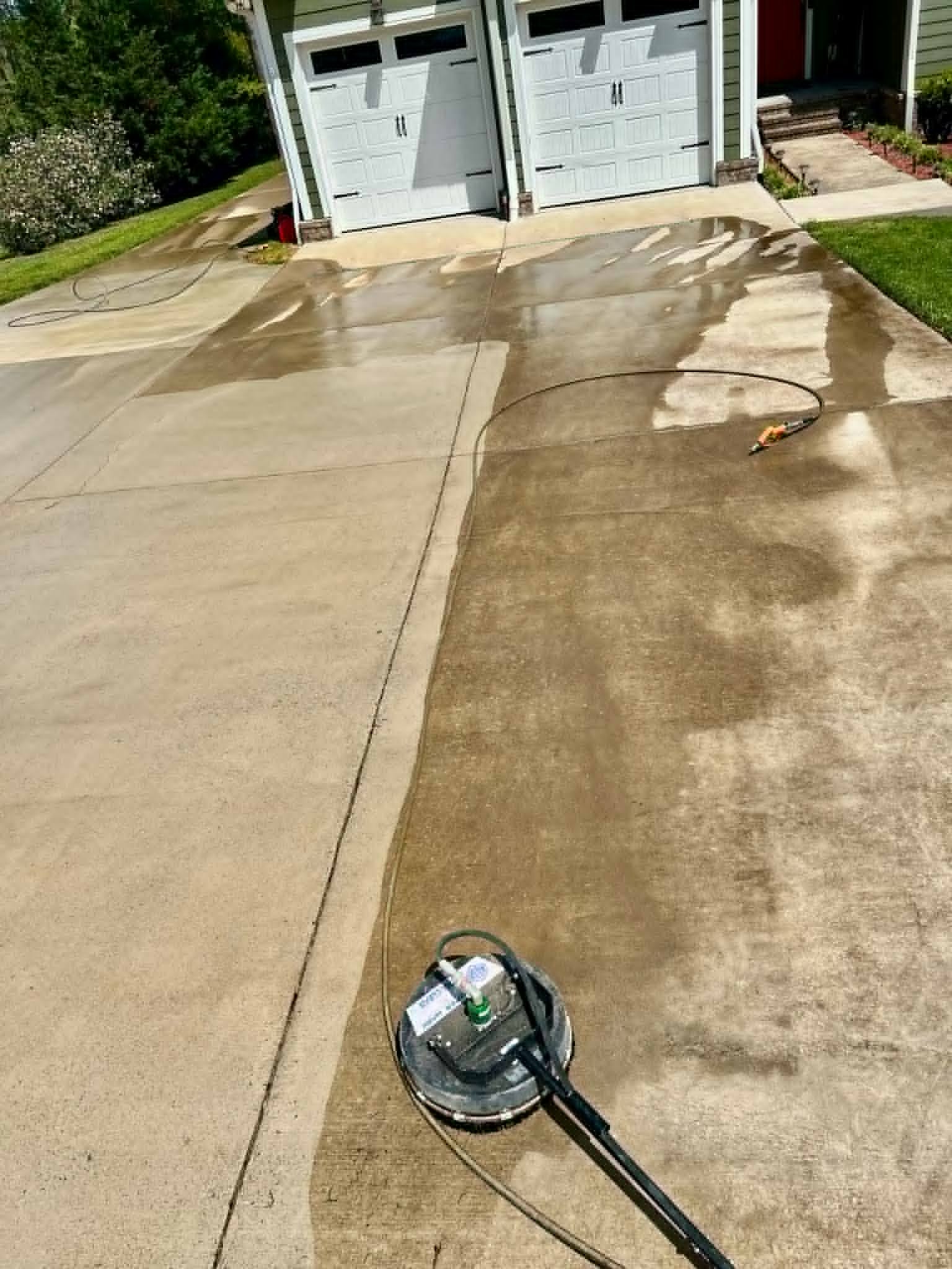 Concrete driveway being pressure washed — surface cleaner in action removing built-up grime
